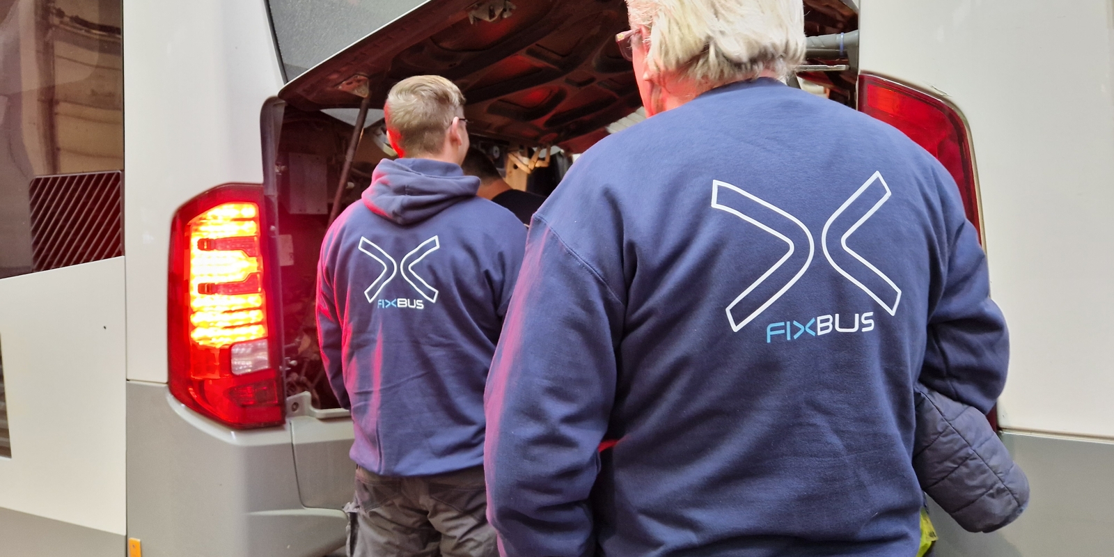 Mecanicien met zijn rug naar de camera. Op zijn trui staat het logo van de Fixbus.